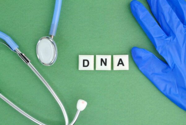 Stethoscope and medical glove next to 'DNA' tiles on a green background, representing paternity testing.