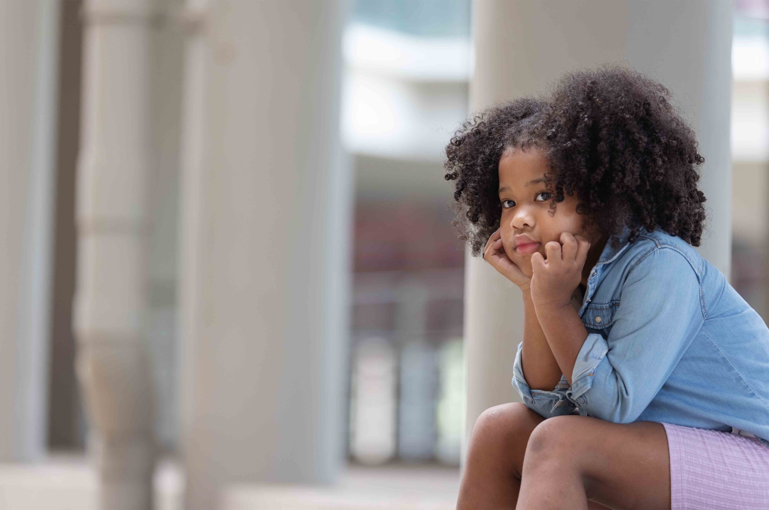 A young girl sitting alone and contemplating her parent's decisions for her custody.