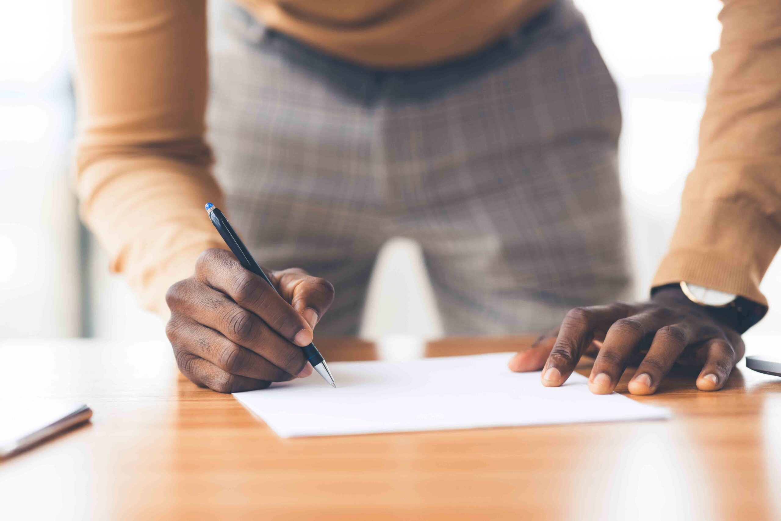 Close-up of a father writing to file a petition to establish paternity at a desk, a tool for his court-ordered paternity testing.