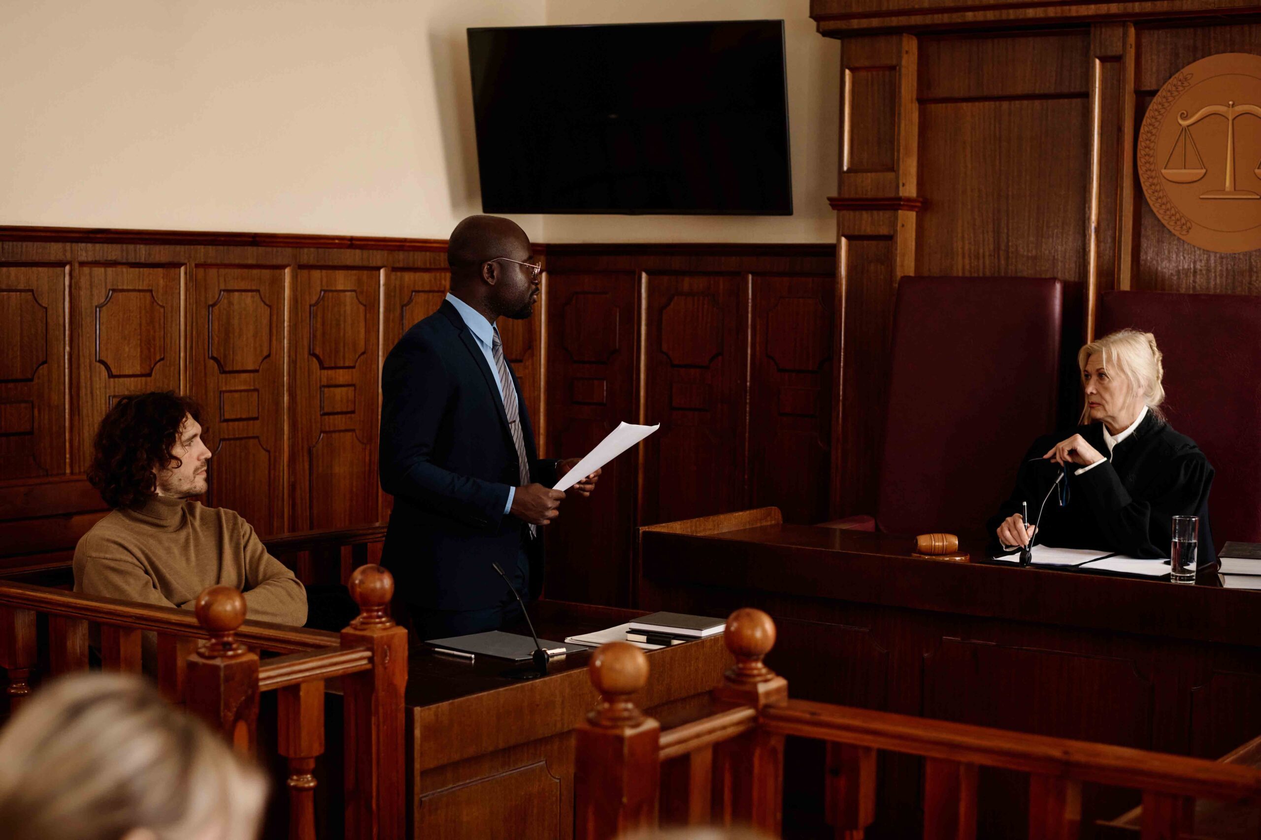 Lawyer presenting a paternity case in court to a judge, with a client sitting in the witness stand.