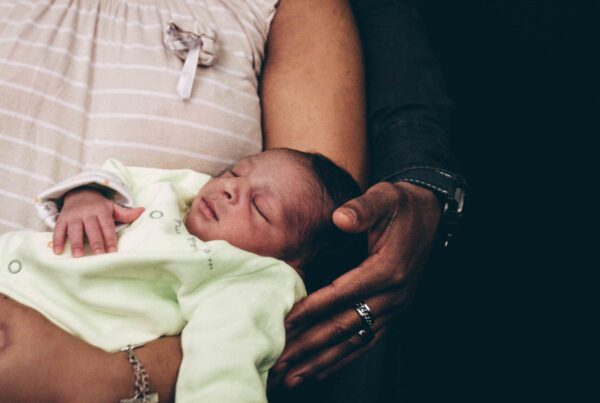 Close-up of a newborn baby sleeping in the arms of parents