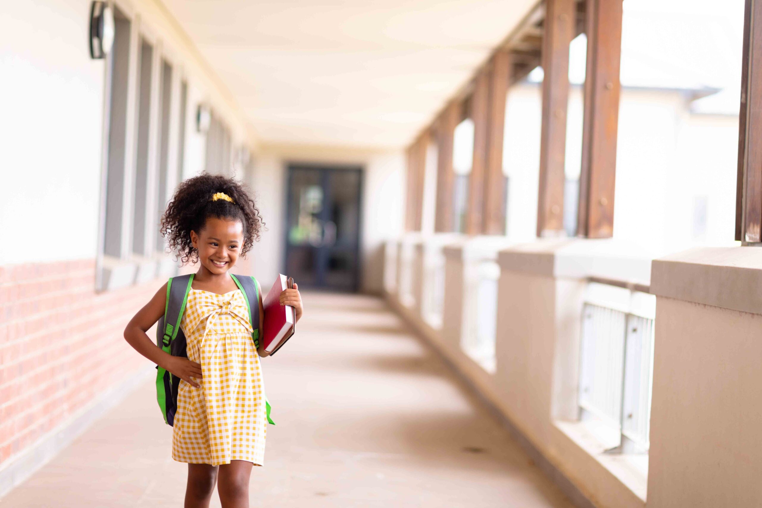 Smiling multiracial elementary schoolgirl with a backpack, representing the impact of child welfare and support.