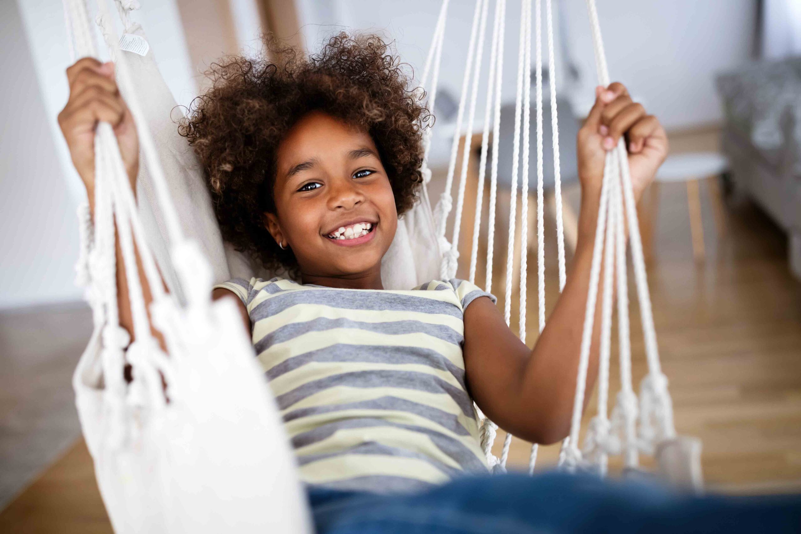 Adorable girl enjoying an indoor swing, illustrating the importance of reducing emotional stress in child support matters