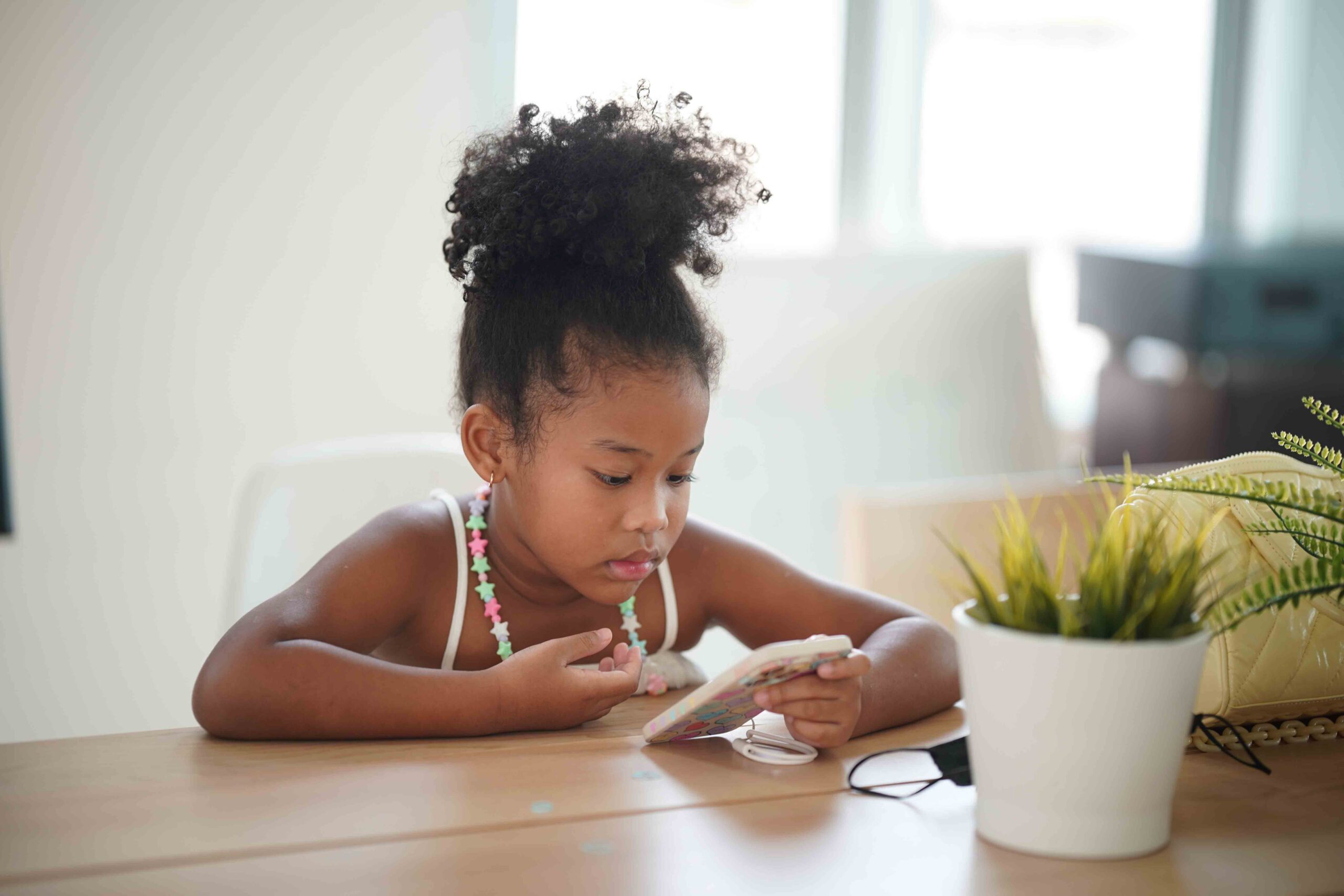 A young girl using a mobile phone, highlighting safety and emergency preparedness measures for children.