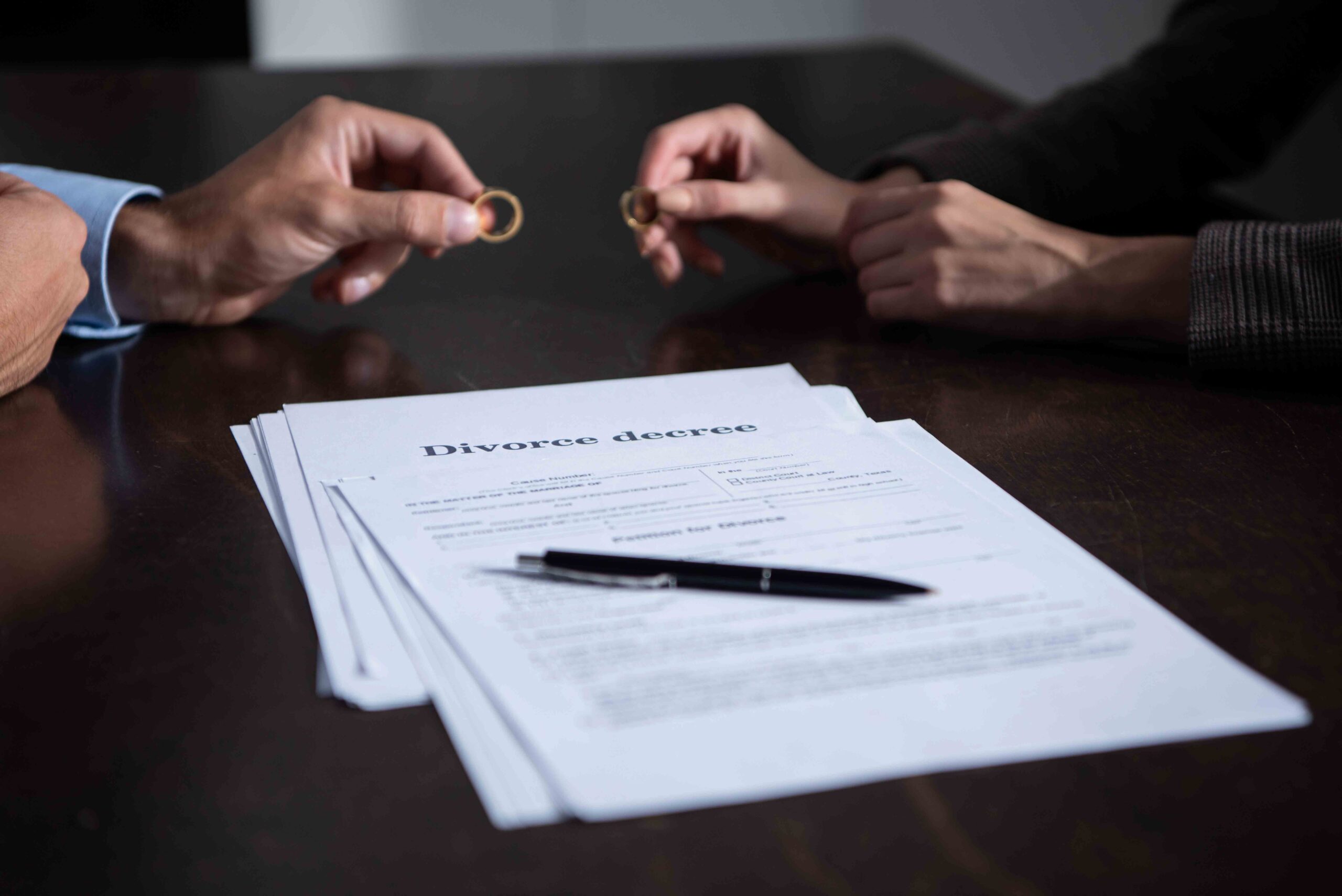 Couple's hands with wedding rings removed over divorce documents, symbolizing the process of filing for divorce