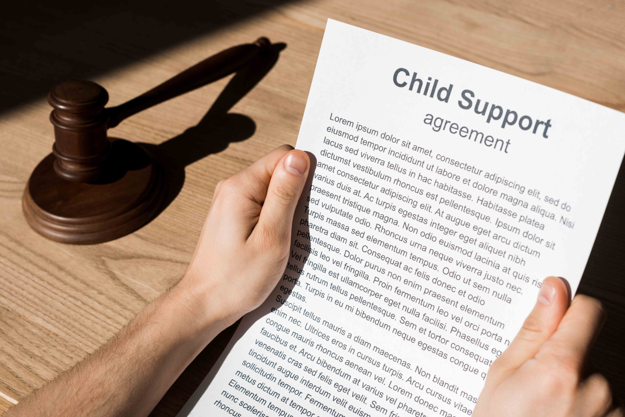 A person holding a child support agreement document next to a gavel, illustrating legal steps to terminate child support in Texas.