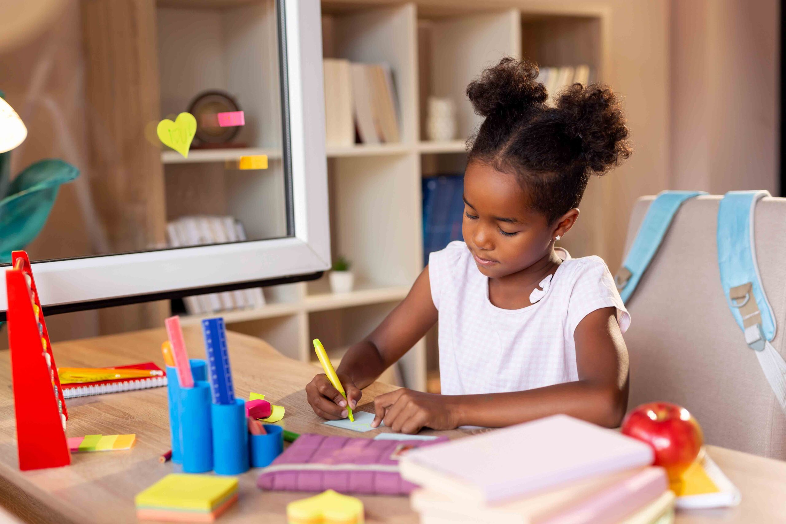 A little girl drawing at a desk, illustrating the importance of addressing a child's educational needs in custody cases.