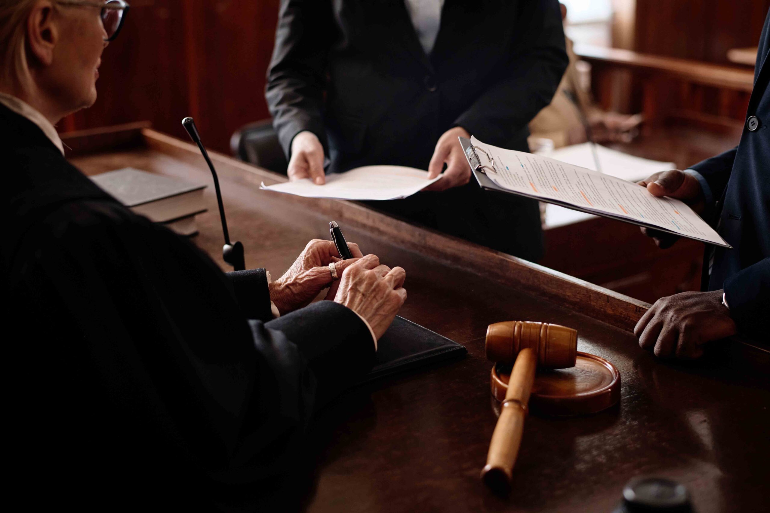 Judge with custody lawyers reviewing documents in court, focusing on evaluating evidence and testimony in the child's best interests.