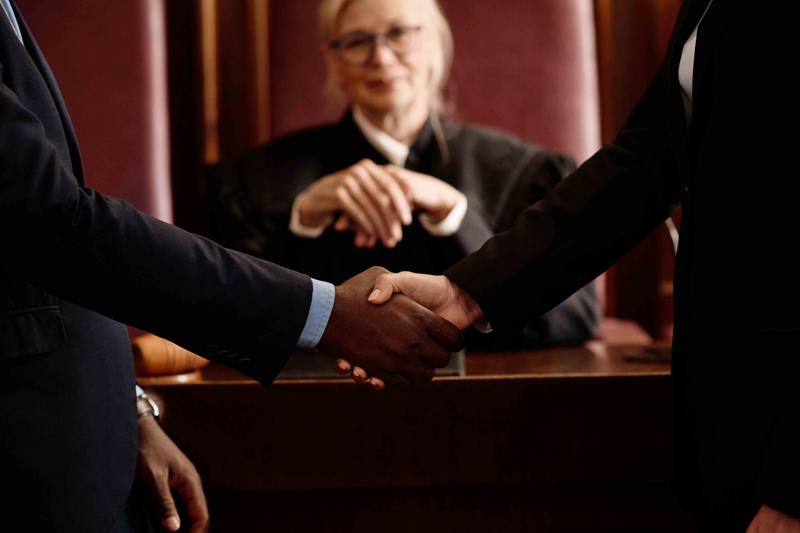 A happy judge with two lawyers shaking hands, approving child support agreement in court, showing legal considerations and the child's best interests