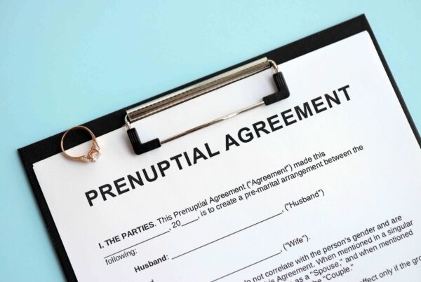 Prenuptial agreement document on a clipboard with a wedding ring, illustrating legal protection of assets in case of divorce