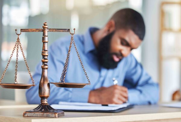 Man writing with a scale of justice on the table, illustrating the importance of temporary custody arrangements in legal disputes