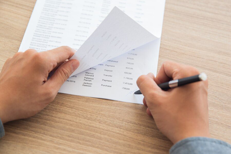 Person reviewing financial transactions from a document with a pen, focusing on maintaining accurate records of child support payments