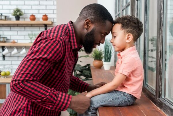 Father leaning forward to talk with his young son in a cozy home setting, symbolizing family discussions about child support and finances