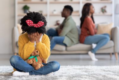 Crying child sitting alone while parents argue in the background, illustrating the emotional impact of removing no-fault divorce in Texas