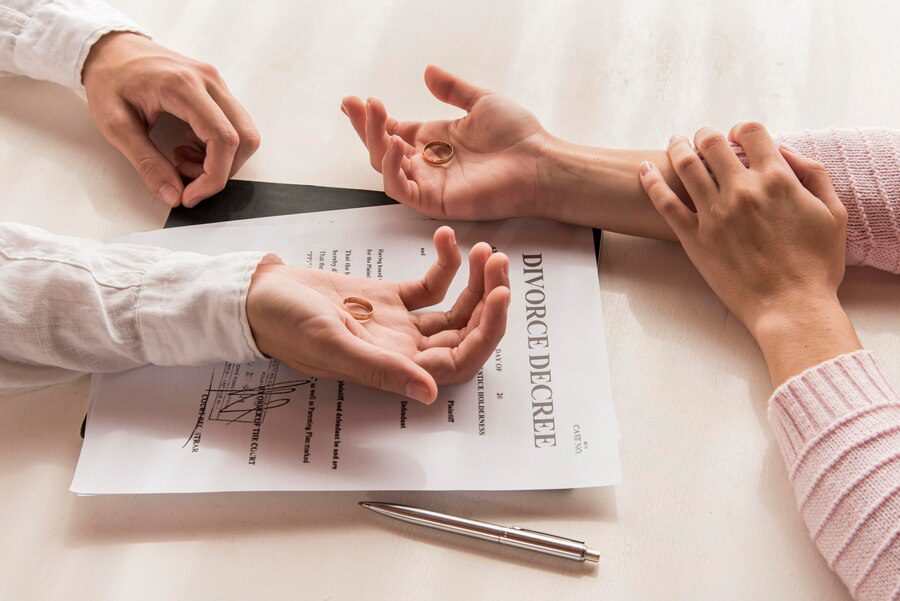 High-angle shot of hands holding wedding rings over a divorce decree, representing the dissolution of a marriage in Texas