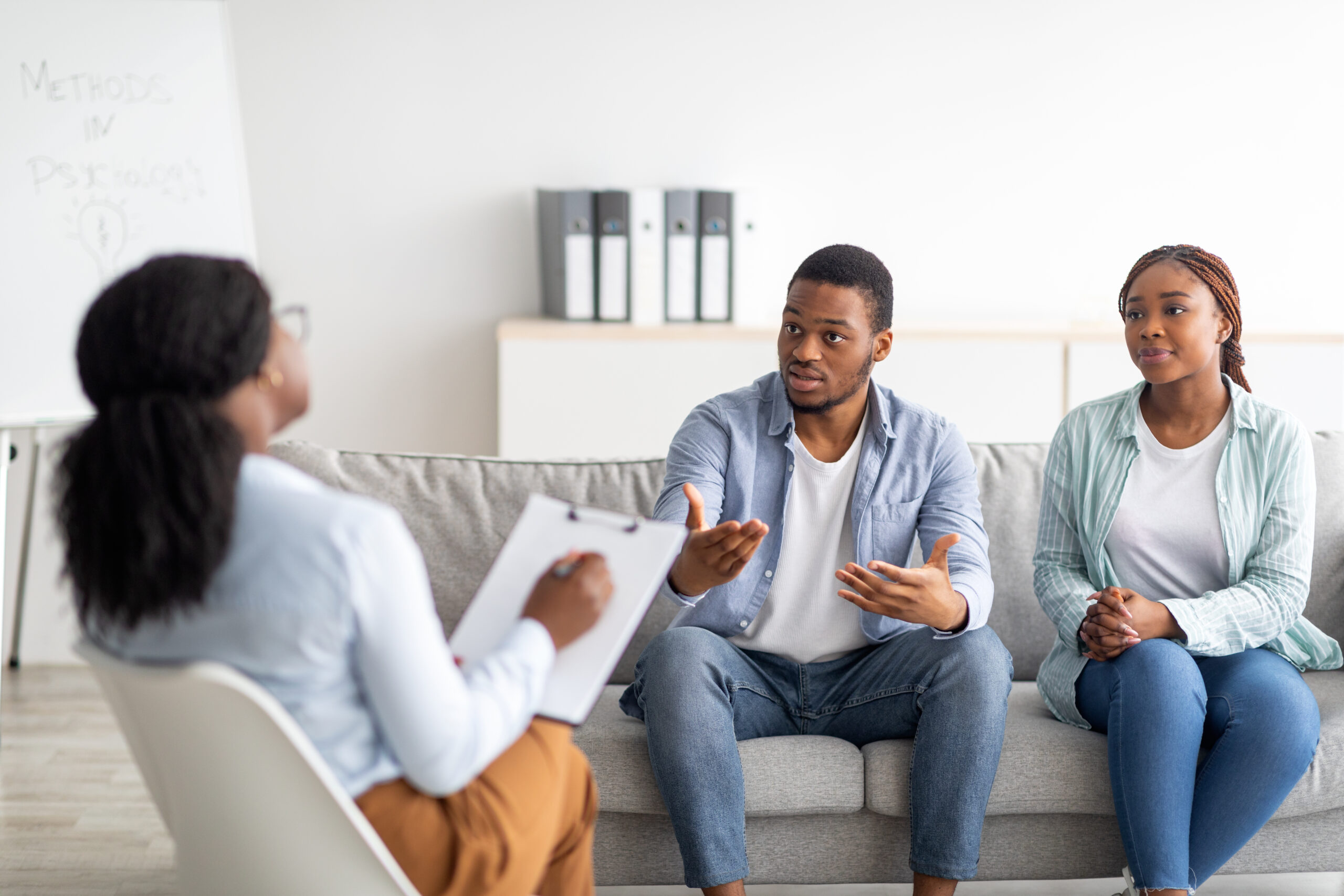 Counsellor guiding parents through a private child custody discussion in office, emphasizing confidentiality in resolving disputes outside of court