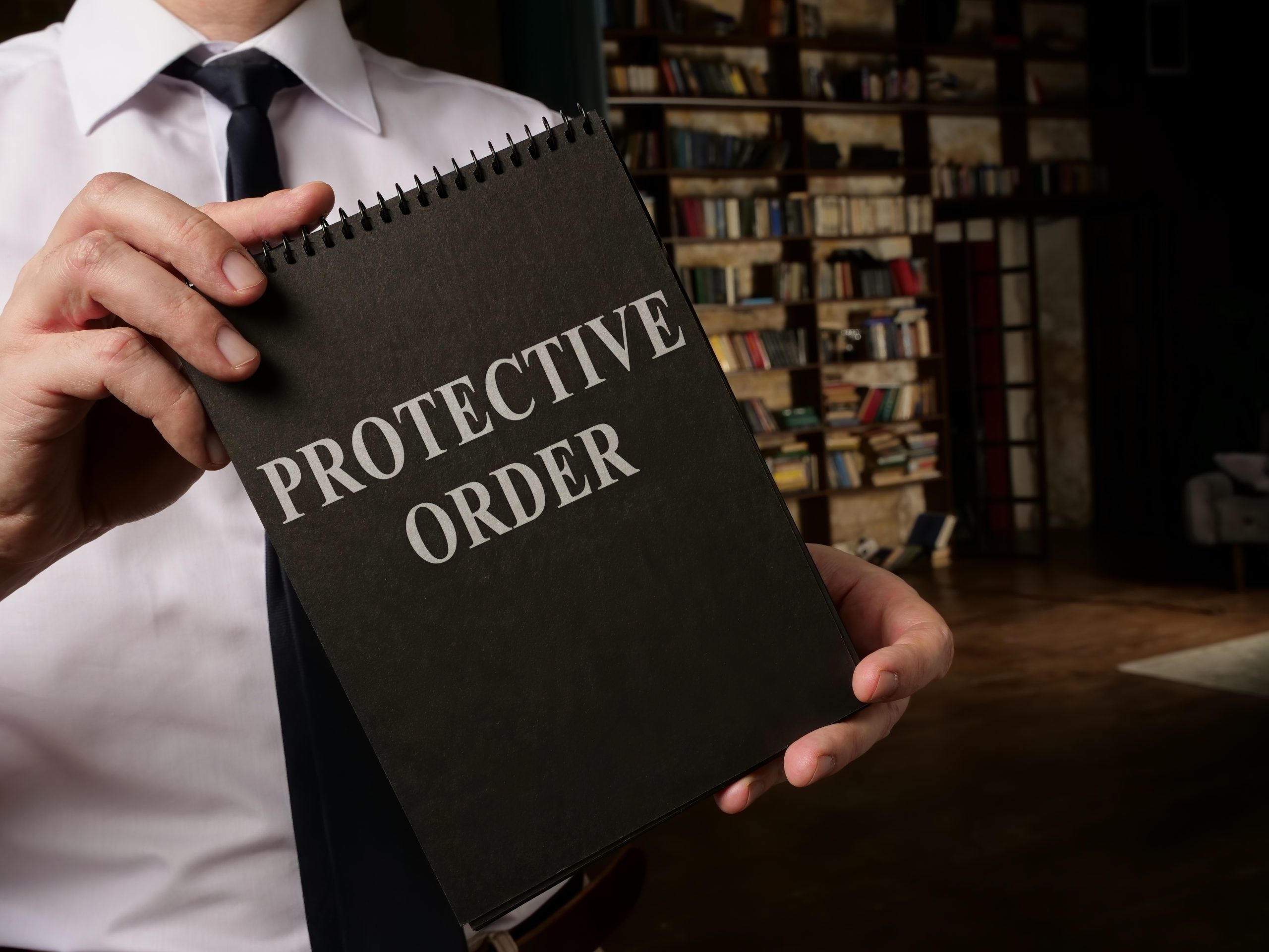 A lawyer holding a notepad with "Protective Order" lettering on the cover