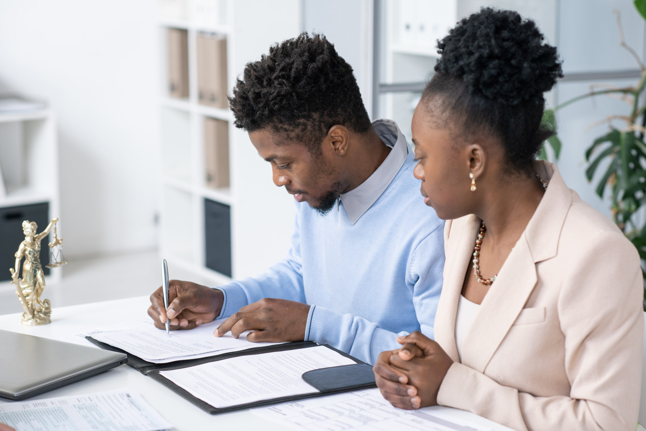 A man and woman discuss prenuptial agreement details at a table with papers and a laptop