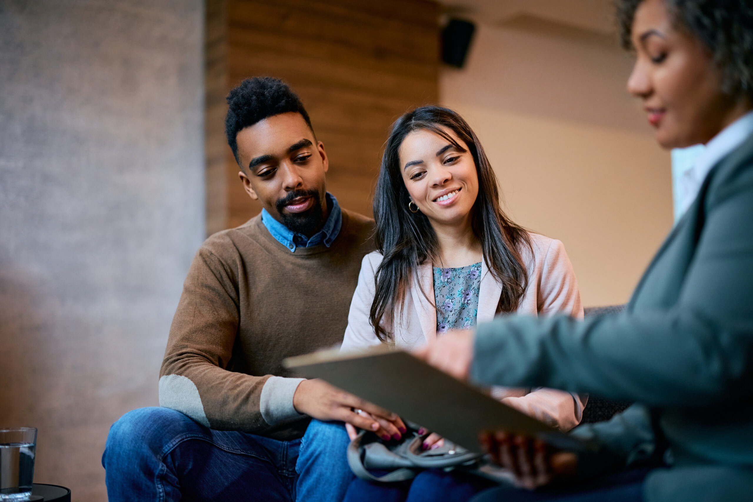 A couple sitting on a couch, reviewing a tablet, discussing how to get a prenuptial agreement