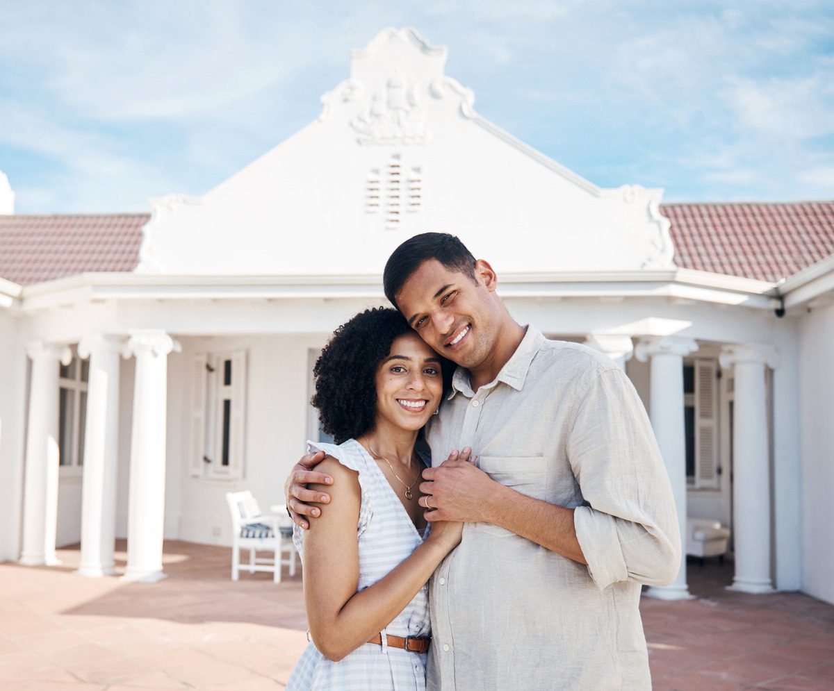 Couple Smiling and Holding Hands in Front of a Wedding Venue