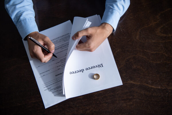 A man signing a divorce agreement, representing a self-managed divorce process without legal assistance