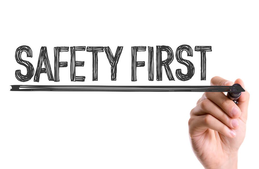 A hand writing "Safety First" on a whiteboard, emphasizing the importance of safety measures