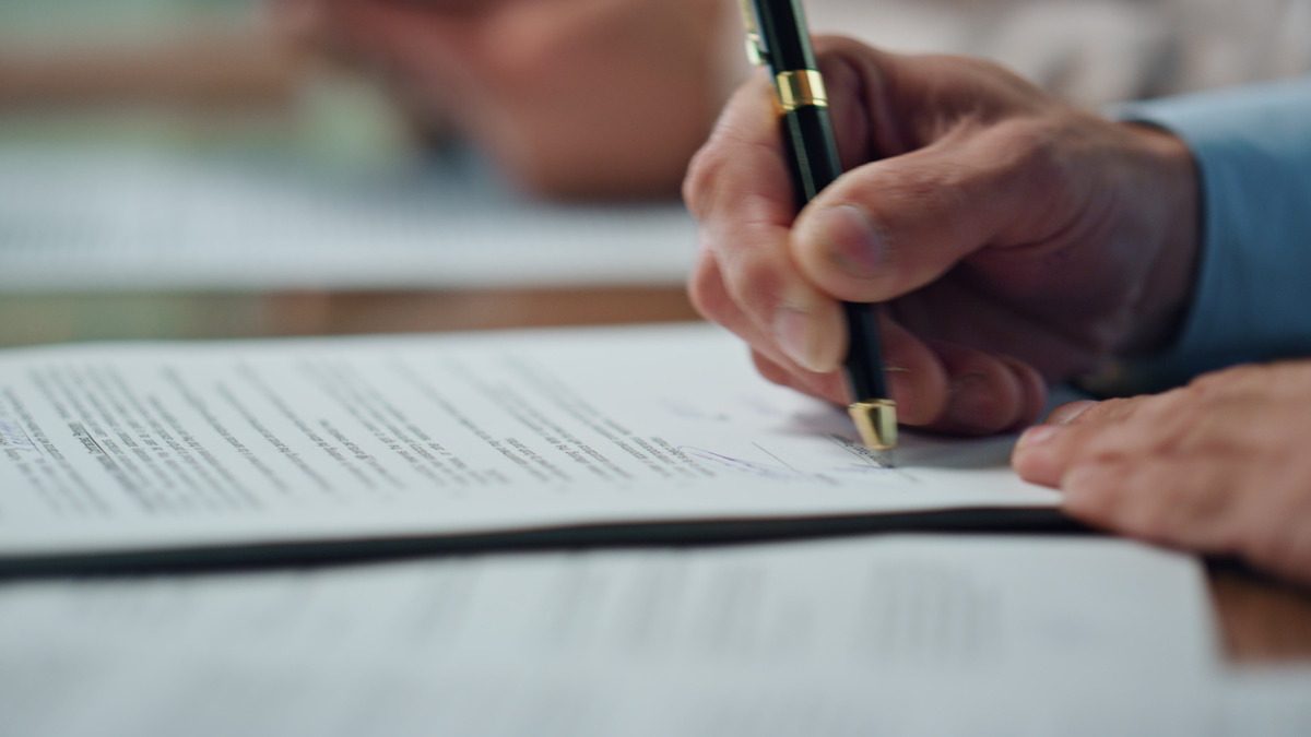 A person signing a document with a pen, possibly related to legal matters concerning child support termination