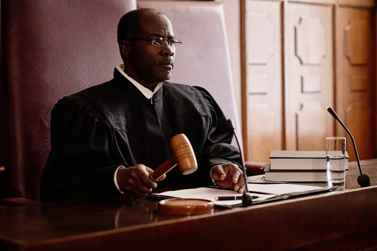 A judge at a desk holding a gavel, symbolizing authority and decision-making in a courtroom setting