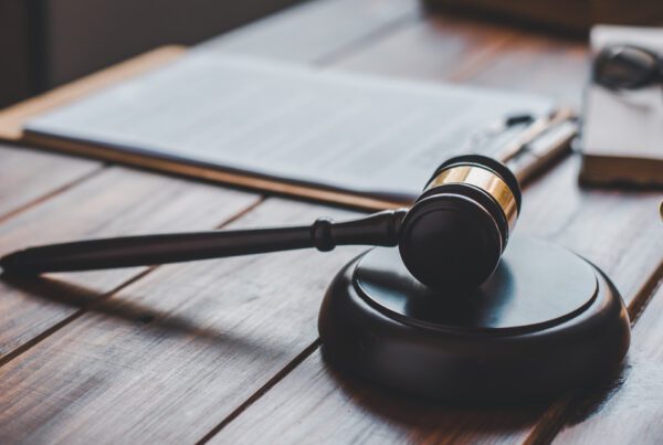 A lawyer's gavel rests beside law books on a wooden table, symbolizing legal authority and knowledge