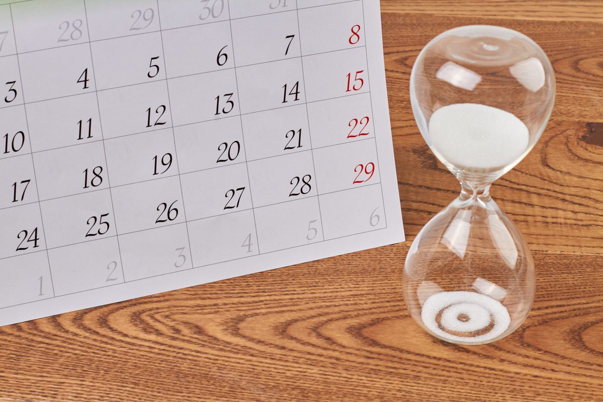 A sand timer on a table beside a calendar, symbolizing the passage of time and legal duration of a restraining order