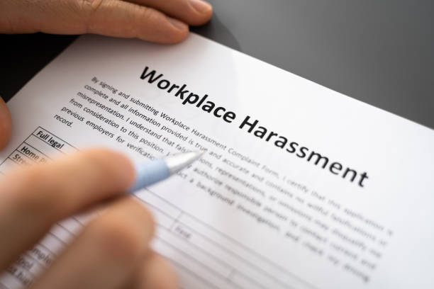 A person completing a workplace harassment form, emphasizing the importance of reporting and addressing such issues