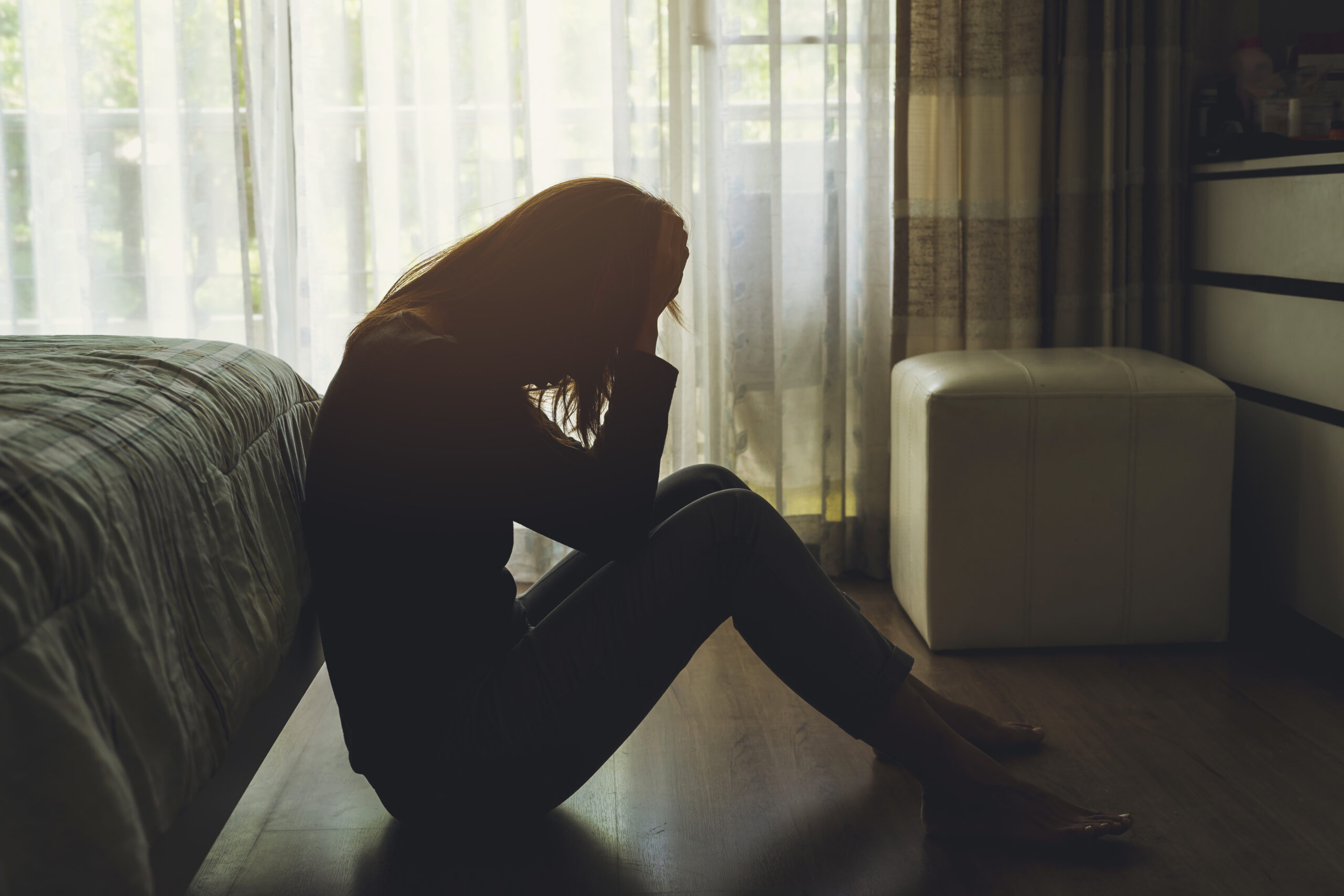 A woman crying in a dark bedroom