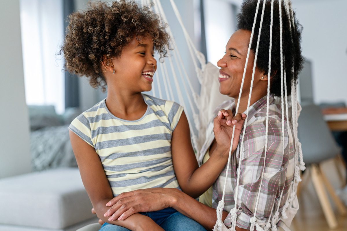 A child sitting on her mother's lap while laughing