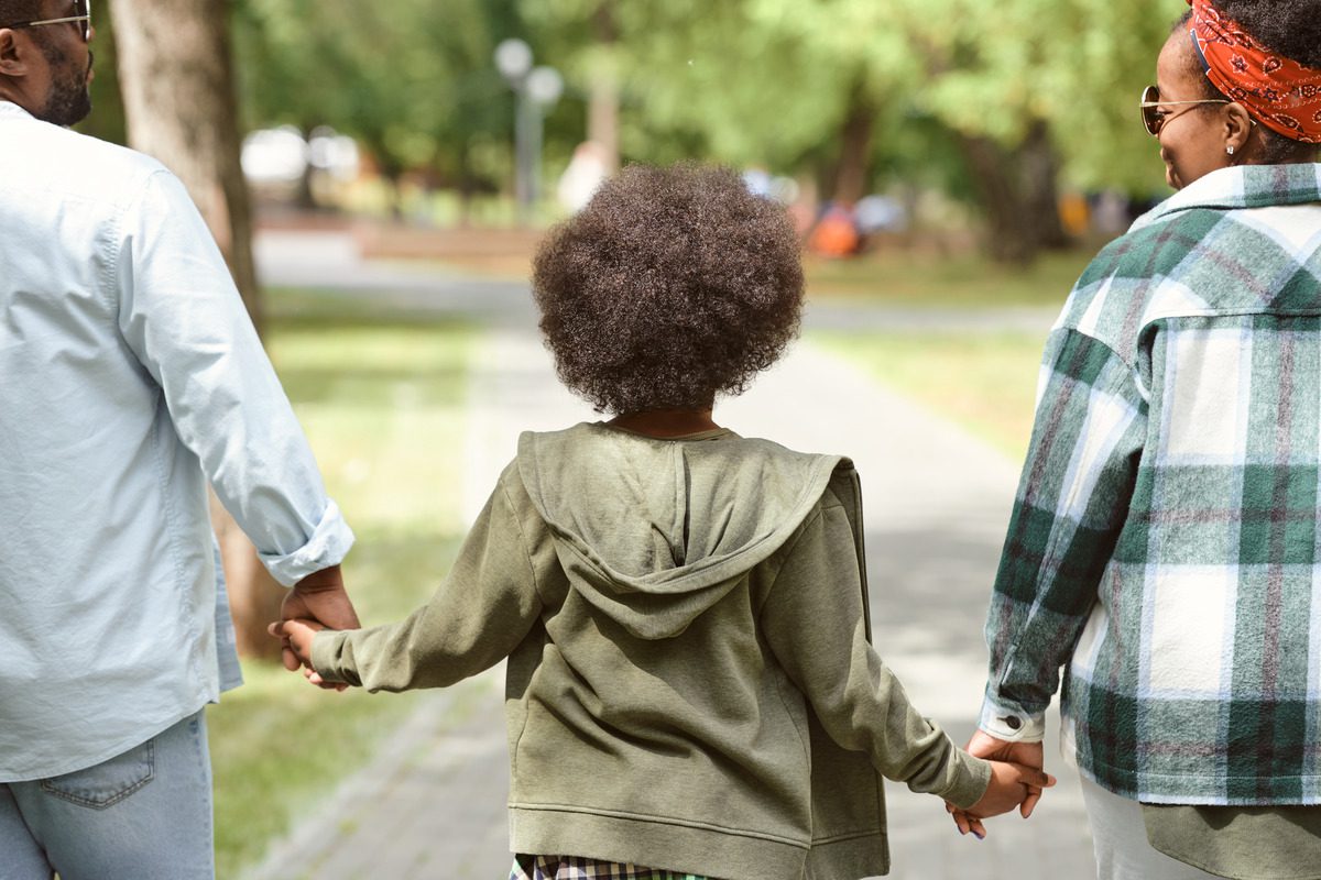 A child holding the parent's hands while walking