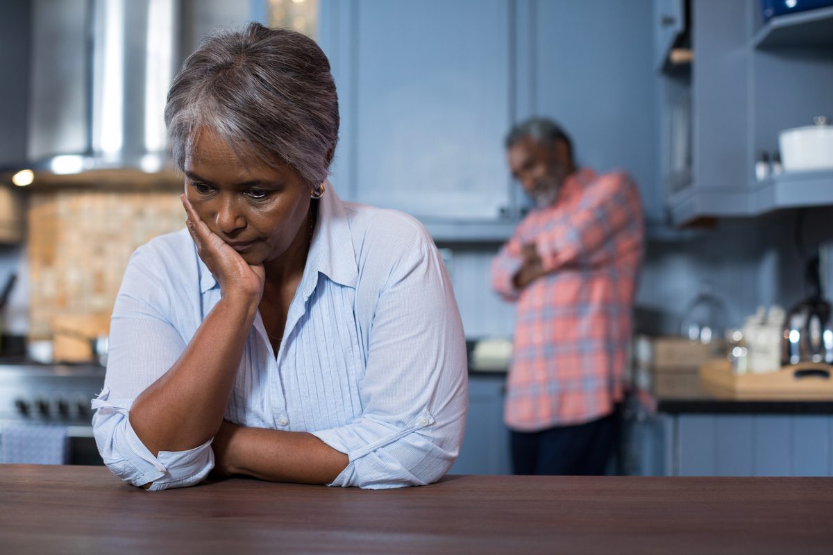 A sad woman with a disappointed man in the background