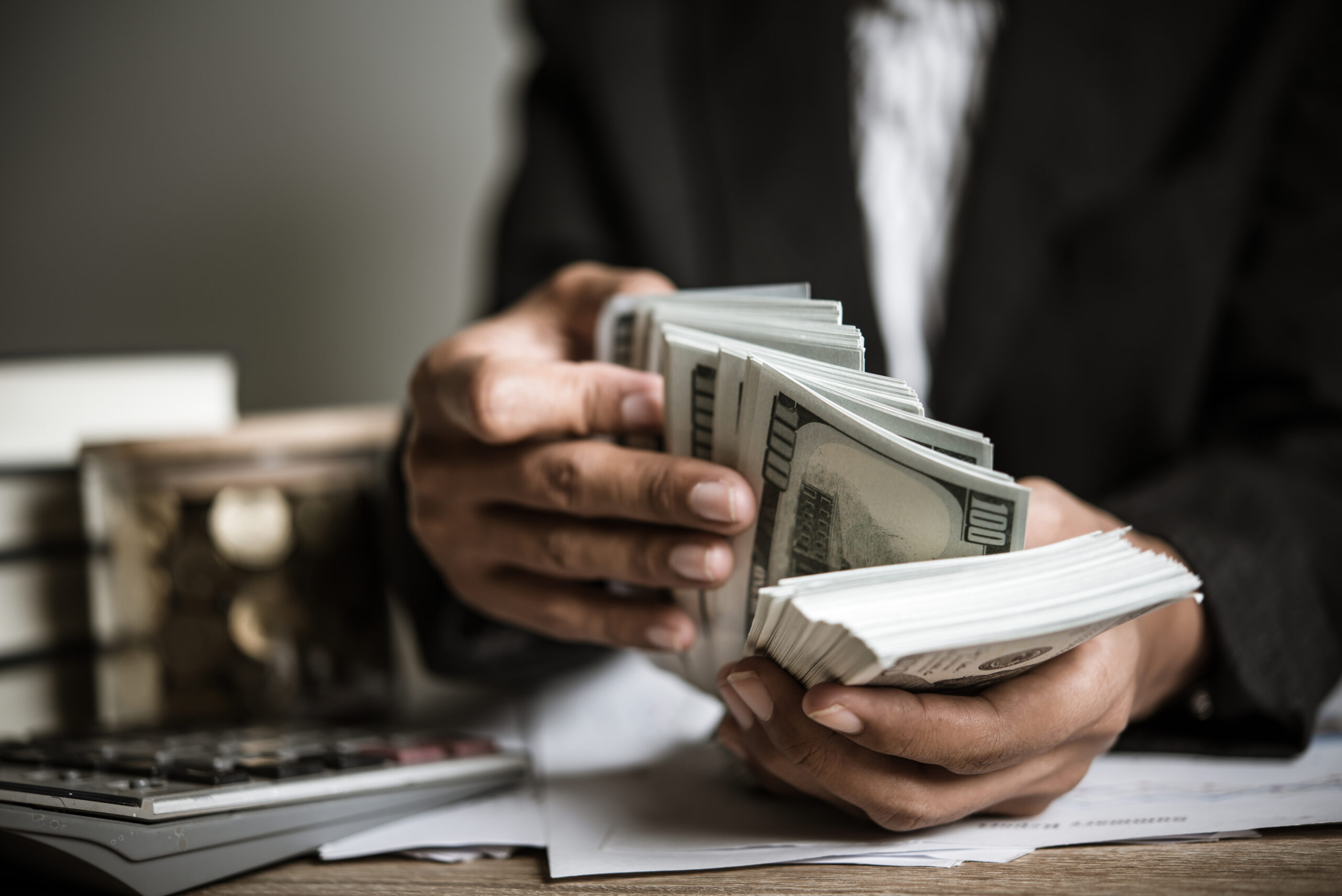 A person counting stacks of money in cash