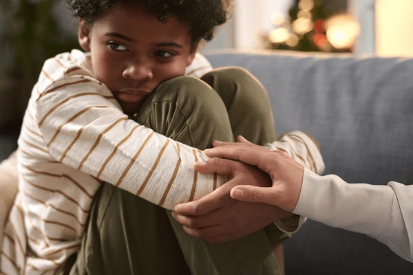 A parent or therapist comforting a child experiencing anxiety, representing childhood mental health support, emotional resilience, and compassionate parenting strategies