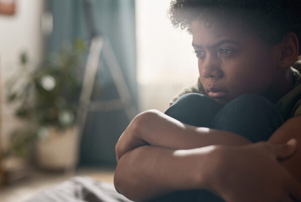 A sad child sitting alone, representing childhood anxiety, mental health awareness, and the emotional well-being of youth in a home setting