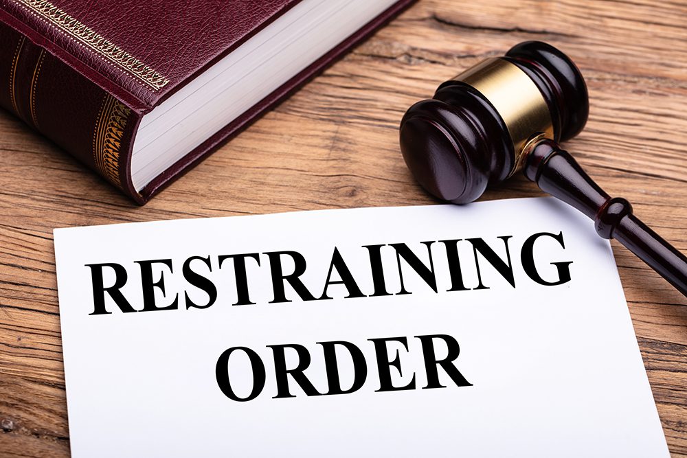Formal restraining order document with a judge's gavel and law book, representing legal protection from harassment, domestic violence litigation, and family court injunction services