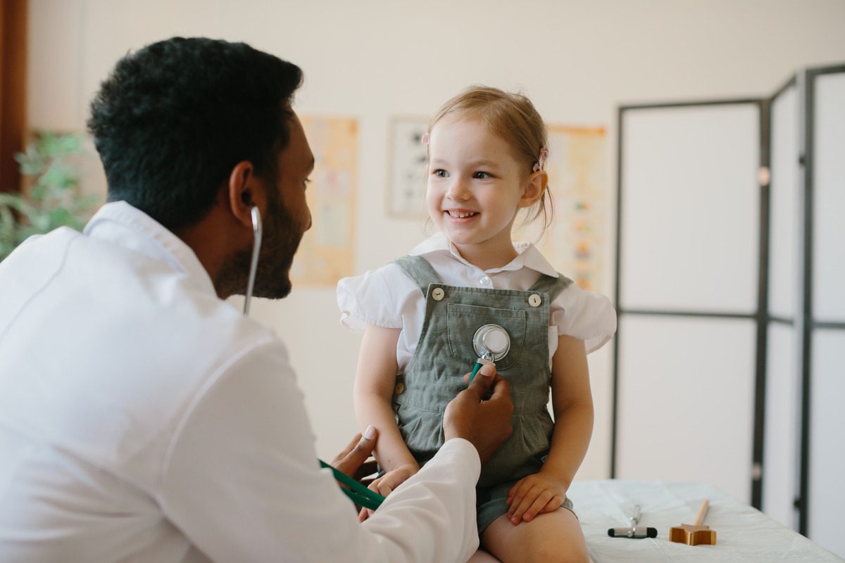 Close-up of a doctor performing a physical checkup on a toddler in a bright pediatric office