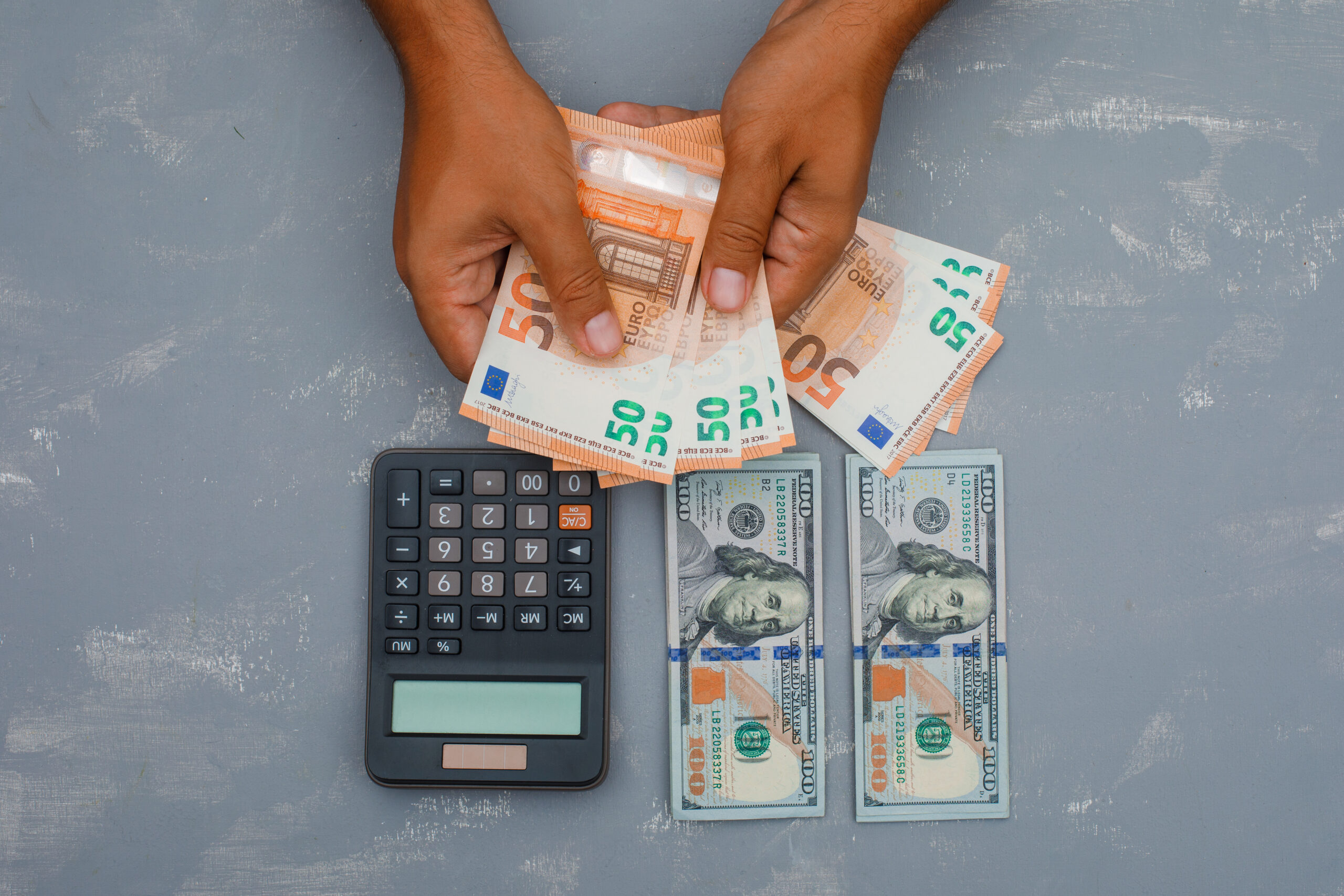 Money management and financial planning concept with hands counting euro banknotes, U.S. dollar bills, and calculator, representing budgeting, currency exchange, personal finance, and cash flow management.