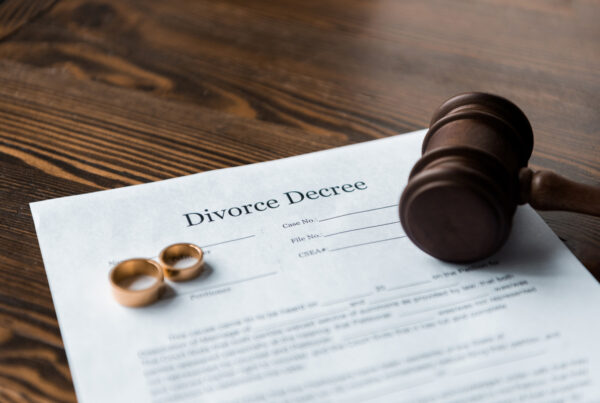 Divorce decree document with wedding rings and judge gavel on wooden table, representing legal separation, marriage dissolution, and family law proceedings