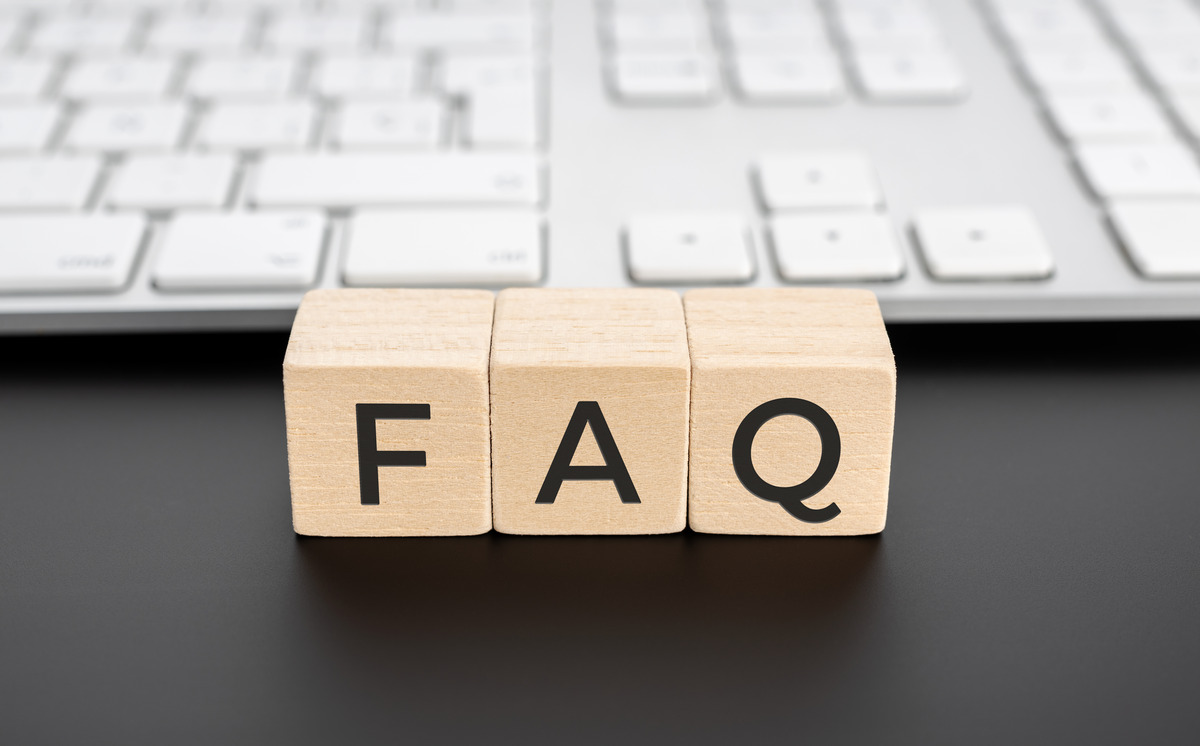 FAQ wooden letter blocks on desk with computer keyboard in background, representing frequently asked questions, customer support, help center resources, and online information services.