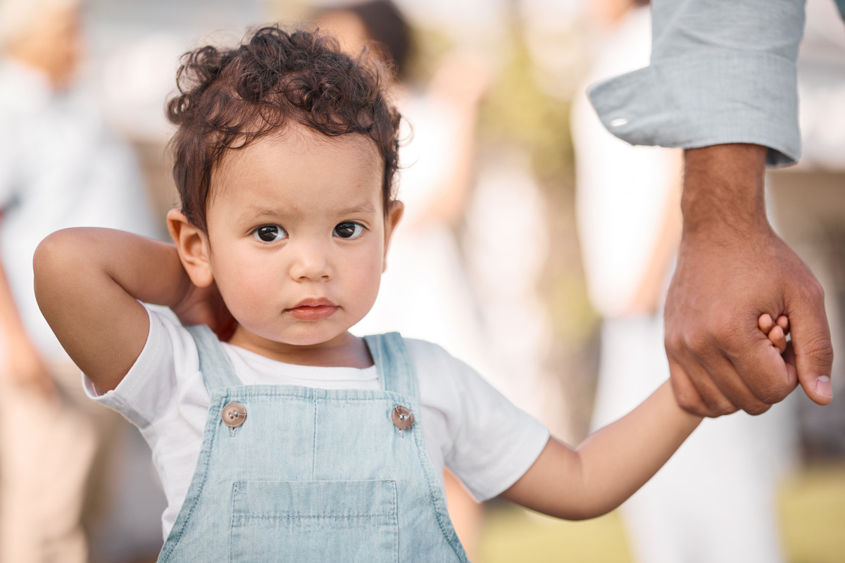 Young child holding a parent’s hand outdoors, representing child safety, parental care, family support, and healthy parent-child relationships.