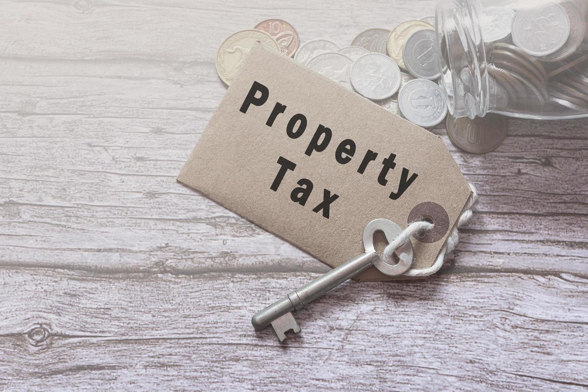 Property tax tag with a key and spilled coins on a wooden surface, symbolizing real estate taxation, property ownership costs, tax obligations, estate planning, and financial aspects of property law.
