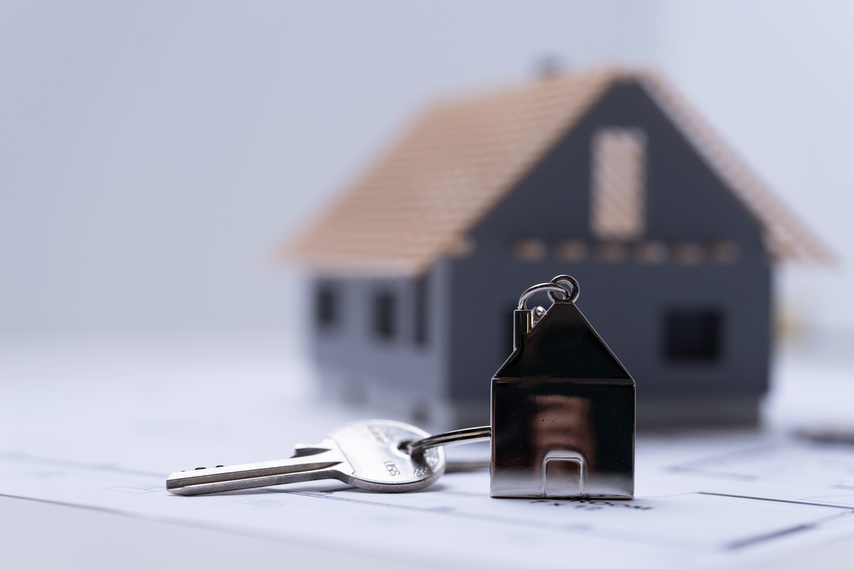 House keys with a miniature home model on property documents, representing real estate ownership, marital property division, home ownership, divorce asset distribution, property settlements, and family law legal proceedings.