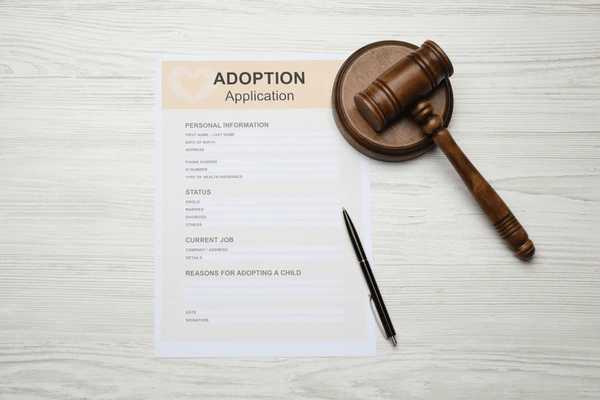 Adoption application form with a judge’s gavel and pen, representing the legal adoption process, adoption paperwork, family law, adoption proceedings, court approval, and attorney guidance for prospective adoptive parent
