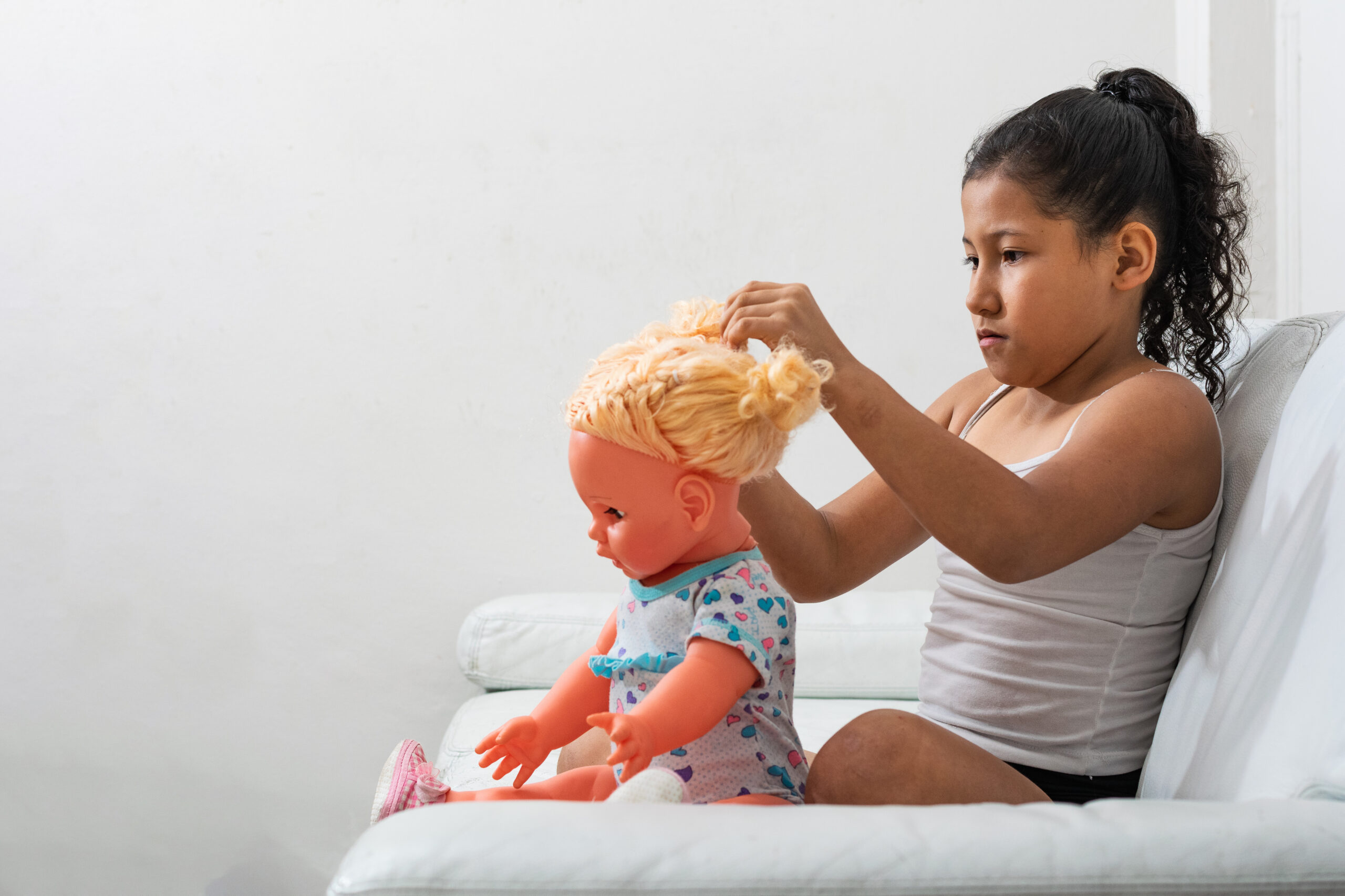 Young child playing with a doll at home, representing child development, emotional well-being, stable home environments, adoption, foster care, child custody, and the importance of nurturing family support.
