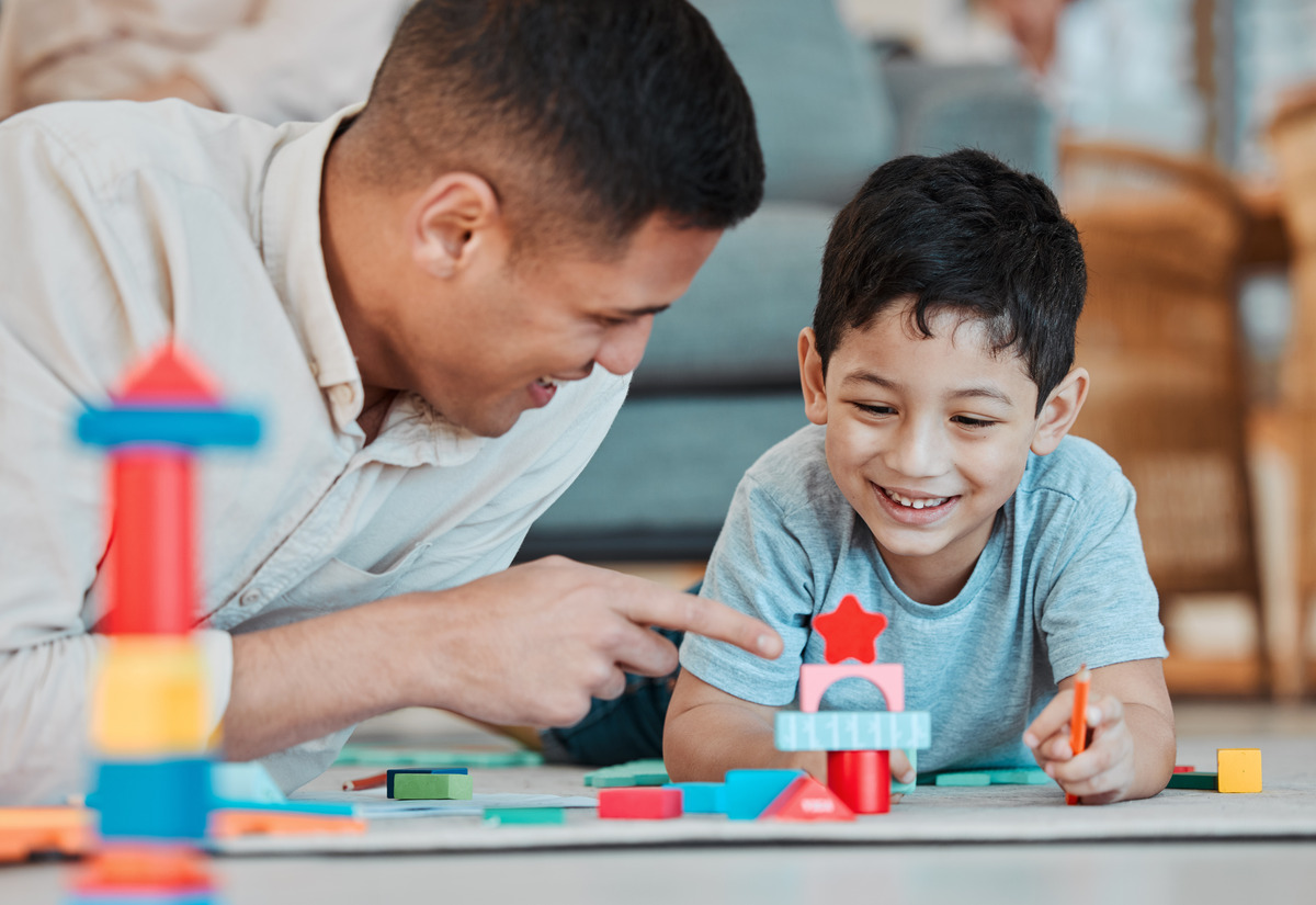 Father spending quality time playing with his son at home, representing positive parenting, healthy parent-child relationships, child development, family bonding, shared parenting, and the importance of a stable home environment for children.